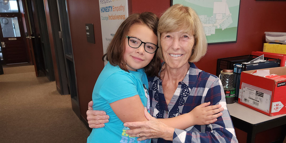 An older woman and young girl looking at the camera with their arms around each other.