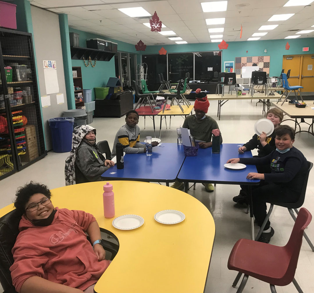 Six teen boys in sitting around a blue table and a yellow table